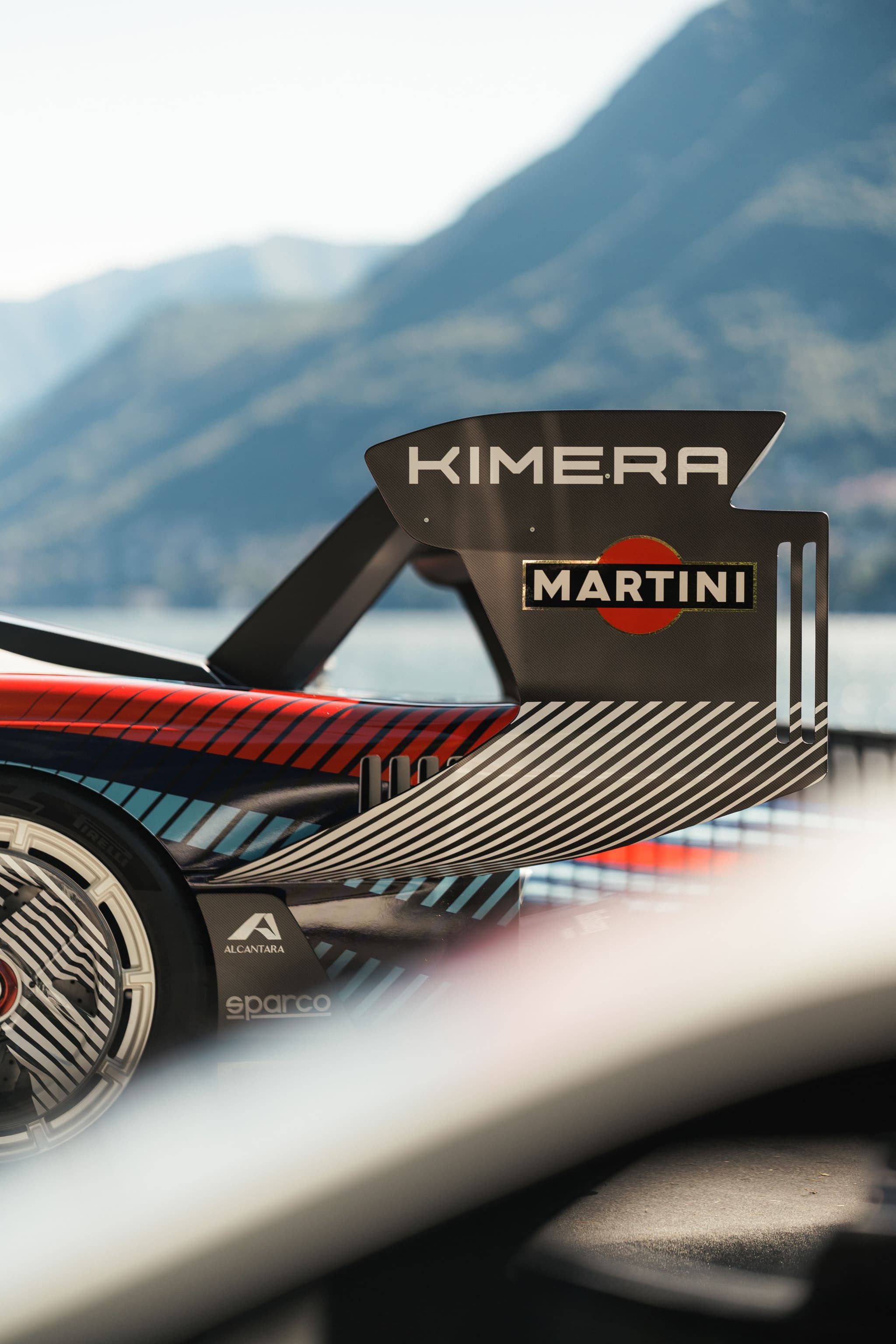 Asa traseira de um Kimera Automobili com decoração Martini, junto a um lago